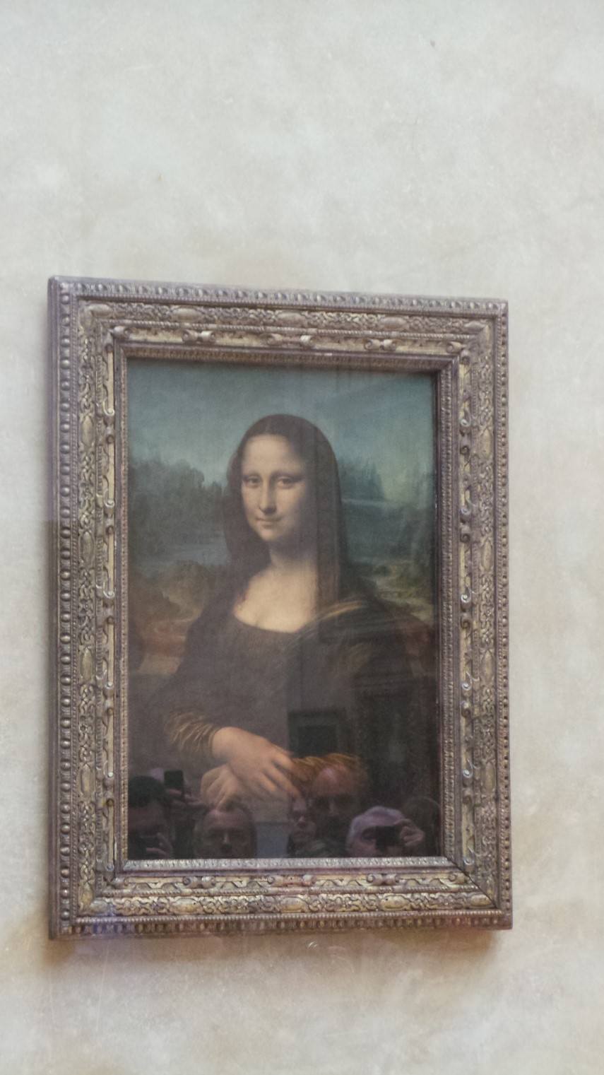 Mona Lisa and quite a few people looking at her through the bullet proof security glass.